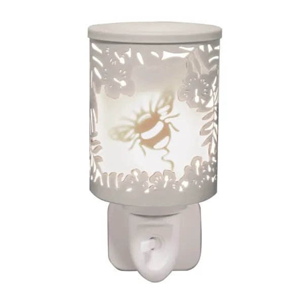 White plug in wax melt burner glowing with a bumblebee motif and floral cut-out detailing, with an on/off switch on the plug base.