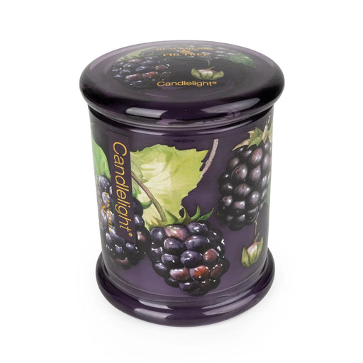 Angled view of Candlelight Blackberry & Fig Tree large glass lidded jar candle in rich purple glass with blackberry design.