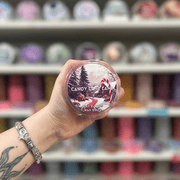 Candy Cane Lane wax melt pot held in hand with colourful wax melt display in the background