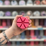 Candy Cane Lane wax melt segments held in hand with colourful wax melt display in the background