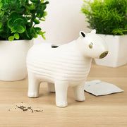 White ceramic capybara chia planter on wooden desk with plant pots and chia seeds