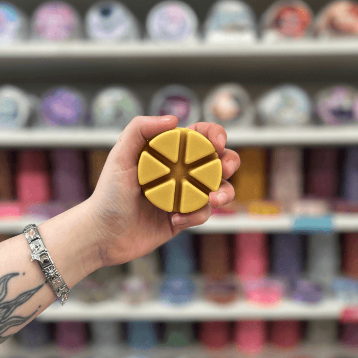 Caramel Latte wax melt segments held in hand with colourful wax melt display in the background