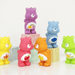 Six Care Bears mini figures posed on pastel display blocks from the Vol. 4 blind box series