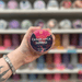 Casablanca Sunrise wax melt pot held in hand with colourful wax melt display in the background