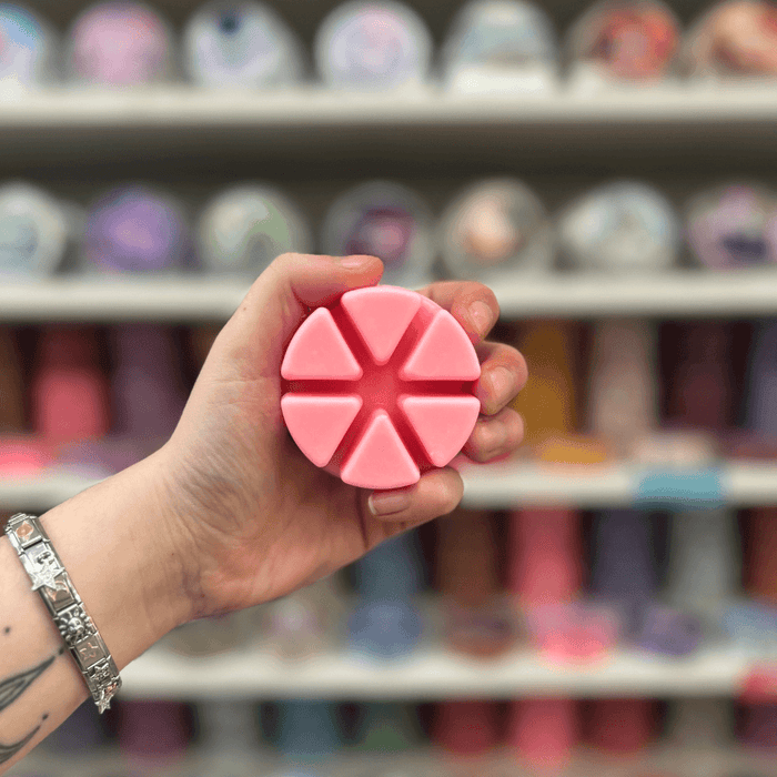 Casablanca Sunrise wax melt segments held in hand with colourful wax melt display in the background