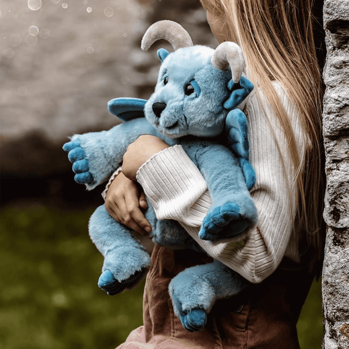 Child cuddling Drawbridge, a sky-blue Bearhouse by Charlie Bears plush gargoyle with soft wings and curled horns