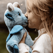 Close-up of a child holding Drawbridge, a soft sky-blue Charlie Bears Bearhouse plush gargoyle with wings and curled horns