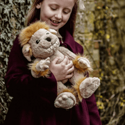Child cuddling Charlie Bears Bedrock ogre plush in a woodland setting