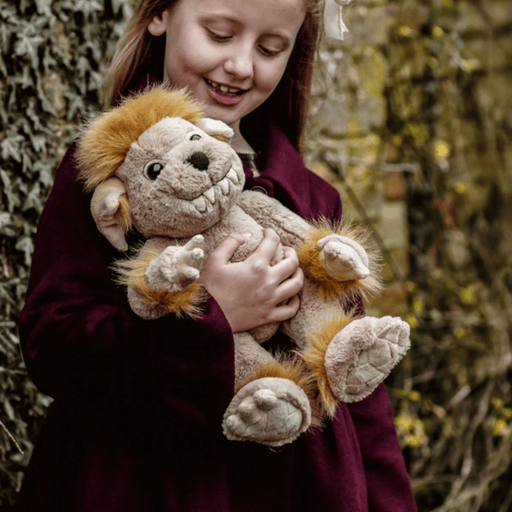 Child cuddling Charlie Bears Bedrock ogre plush in a woodland setting