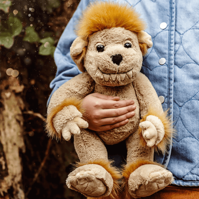 Child holding Charlie Bears Bedrock friendly ogre plush outdoors