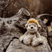 Charlie Bears Bedrock ogre plush sitting on a woodland log