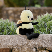 Charlie Bears Bumble Bee yellow plush soft toy sitting outdoors on a stone wall