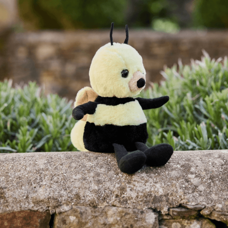 Charlie Bears Bumble Bee yellow plush soft toy sitting outdoors on a stone wall