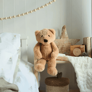 Charlie Bear oatmeal-brown plush teddy sitting in a softly decorated nursery