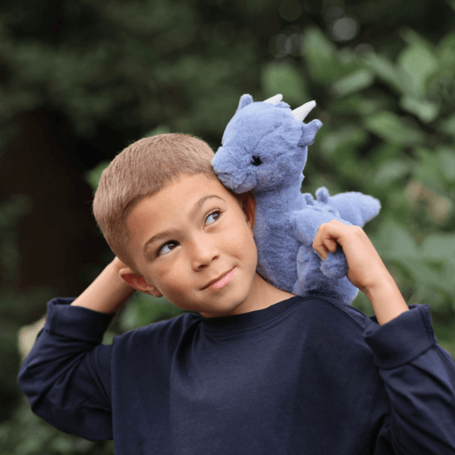 Child cuddling Charlie Bears Draco Dragon denim blue plush outdoors