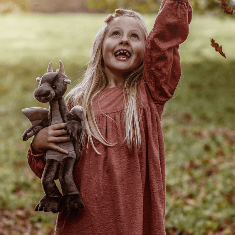 Child holding Clubs brown dragon luxury plush from the Bearhouse by Charlie Bears 2025 collection outdoors