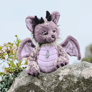Charlie Bears Eragon mythical Tatzelwurm plush displayed outdoors on a stone wall with wings spread