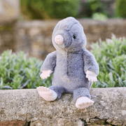 Charlie Bears Mula Mole grey plush soft toy sitting outdoors on a stone wall
