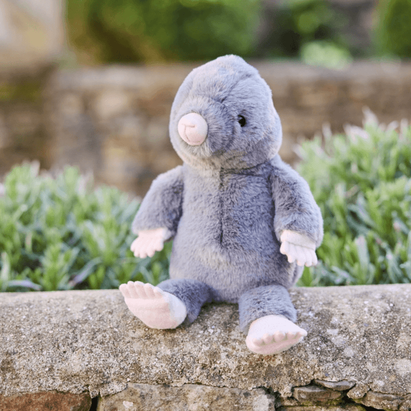 Charlie Bears Mula Mole grey plush soft toy sitting outdoors on a stone wall
