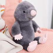 Charlie Bears Mula Mole stone-grey plush soft toy sitting on a pink sofa