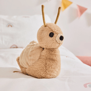 Charlie Bears Saffy Snail oatmeal-brown plush soft toy sitting on a child’s bed