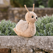 Charlie Bears Saffy Snail oatmeal-brown plush soft toy sitting outdoors