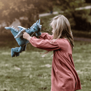Child playing outdoors with Charlie Bears Spades sage-green dragon soft toy