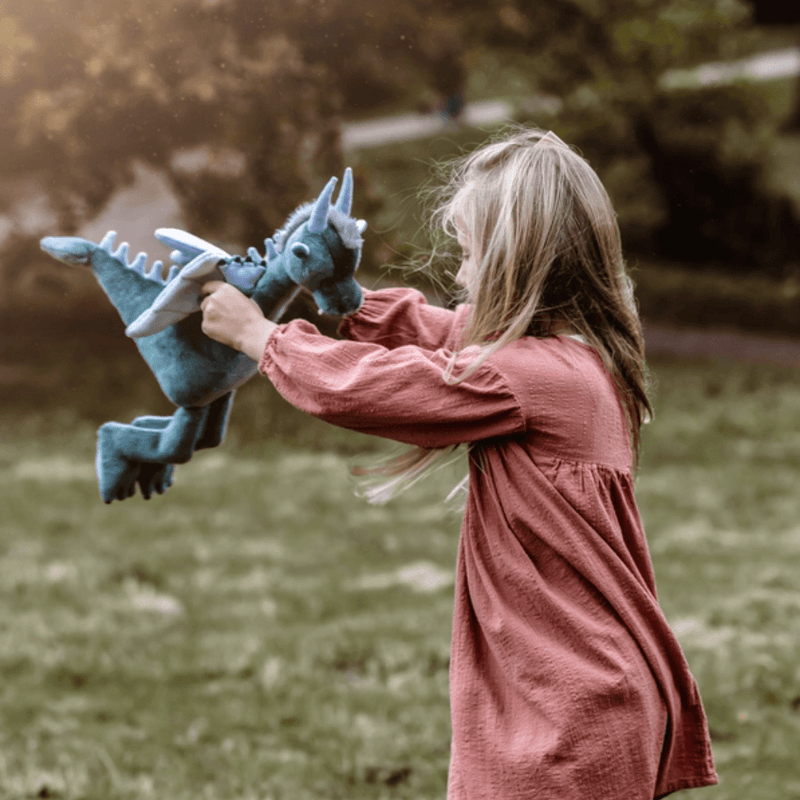 Child playing outdoors with Charlie Bears Spades sage-green dragon soft toy