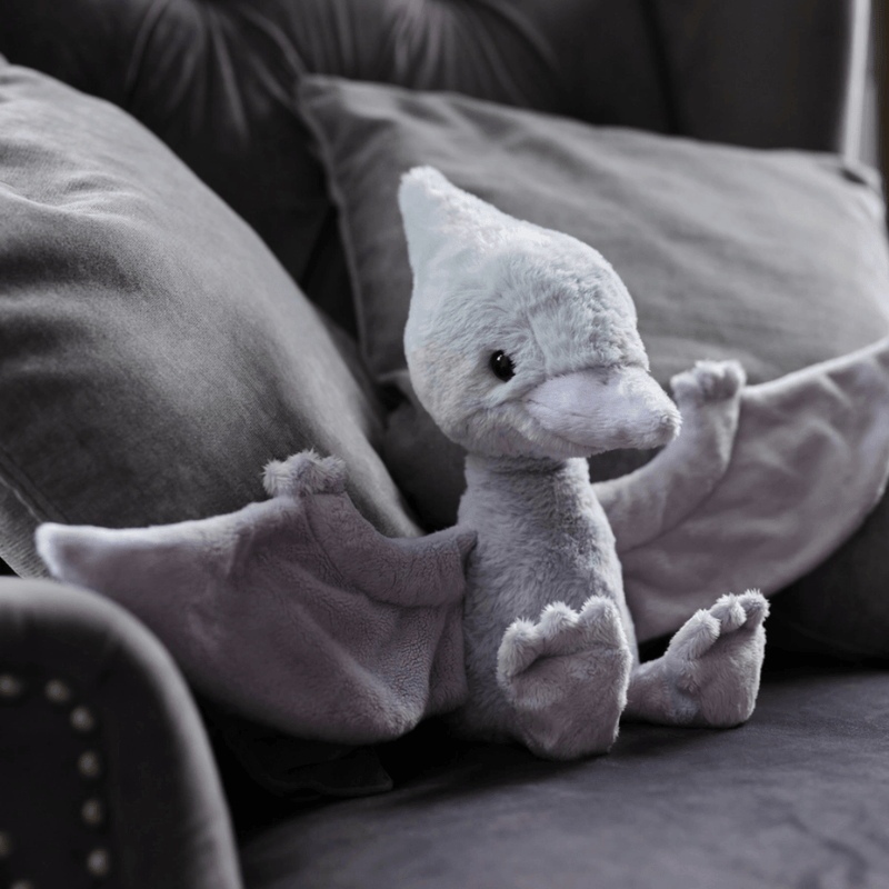 Charlie Bears Wings Pterodactyl cloudy-grey plush soft toy sitting on a sofa