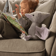 Child reading beside Charlie Bears Wings Pterodactyl plush dinosaur soft toy