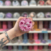 Cherry Marshmallow wax melt pot held in hand with colourful wax melt display in the background
