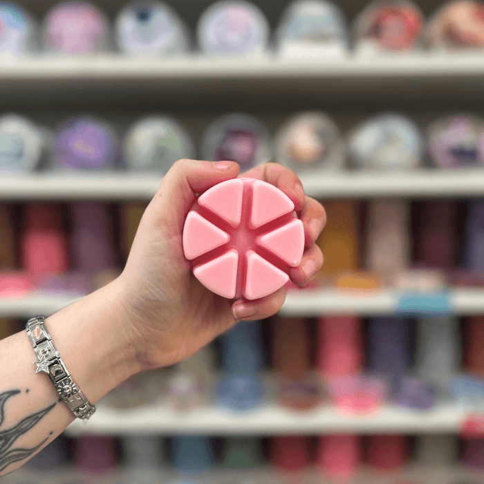 Cherry Marshmallow wax melt segments held in hand with colourful wax melt display in the background