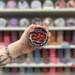 Cinnamon Buns wax melt pot held in hand with colourful wax melt display in the background