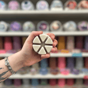 Cinnamon Buns wax melt segments held in hand with colourful wax melt display in the background