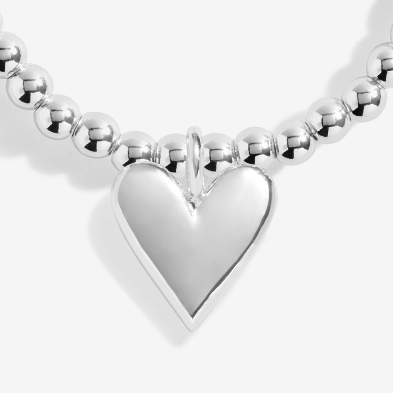 “Close‑up of solid heart charm on beaded Christmas bracelet”
