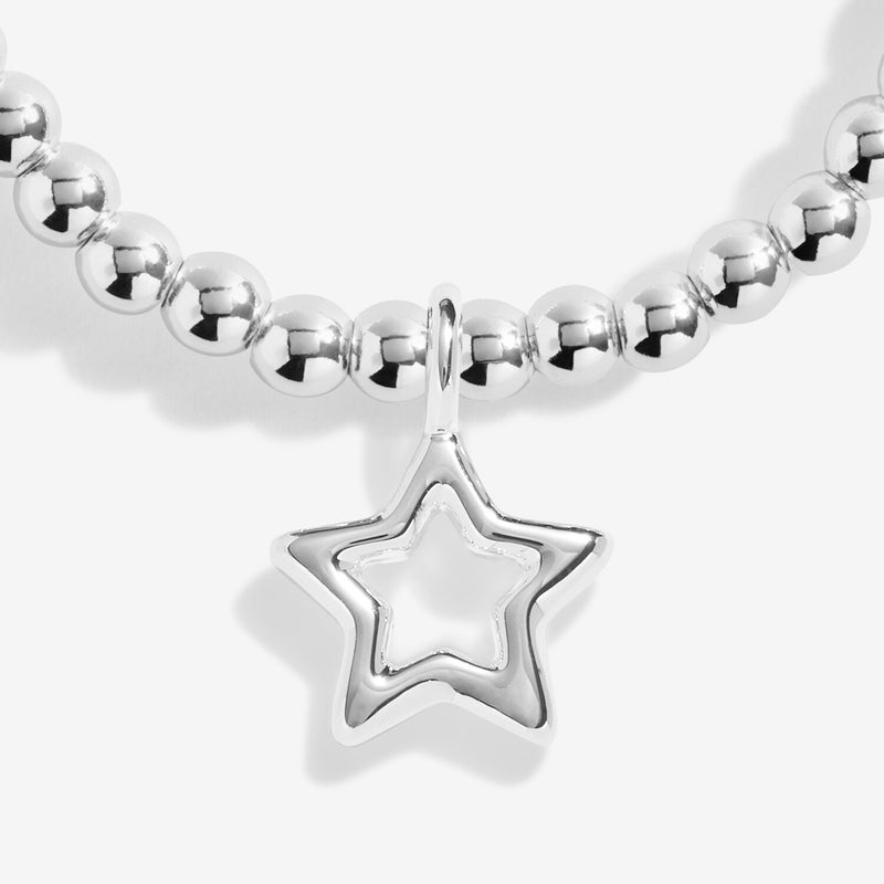 Close‑up detail of open‑star silver charm on children’s beaded bracelet
