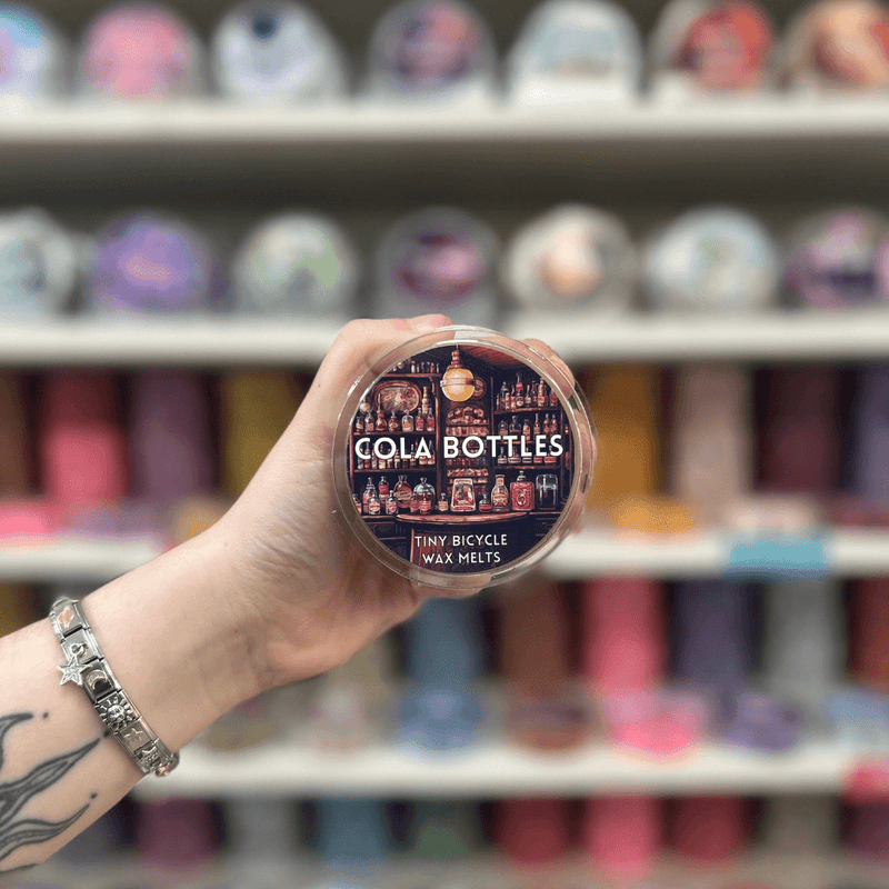 Cola Bottles wax melt pot held in hand with colourful wax melts softly blurred behind