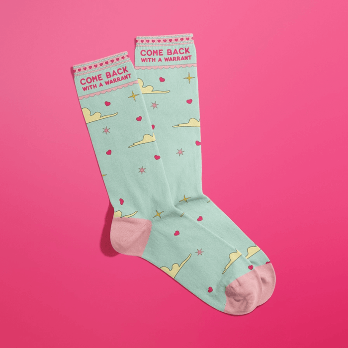 Overlapped mint women’s crew socks with pink accents, cloud and star print, cheeky Come Back With A Warrant text at cuff.