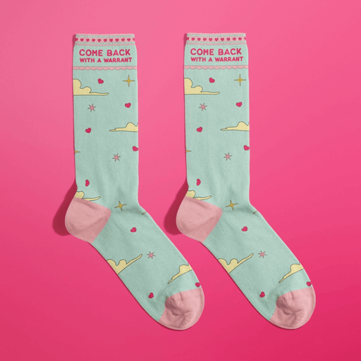 Mint green women’s crew socks with pink toes and heels, clouds, stars and hearts, slogan Come Back With A Warrant, on hot pink background.