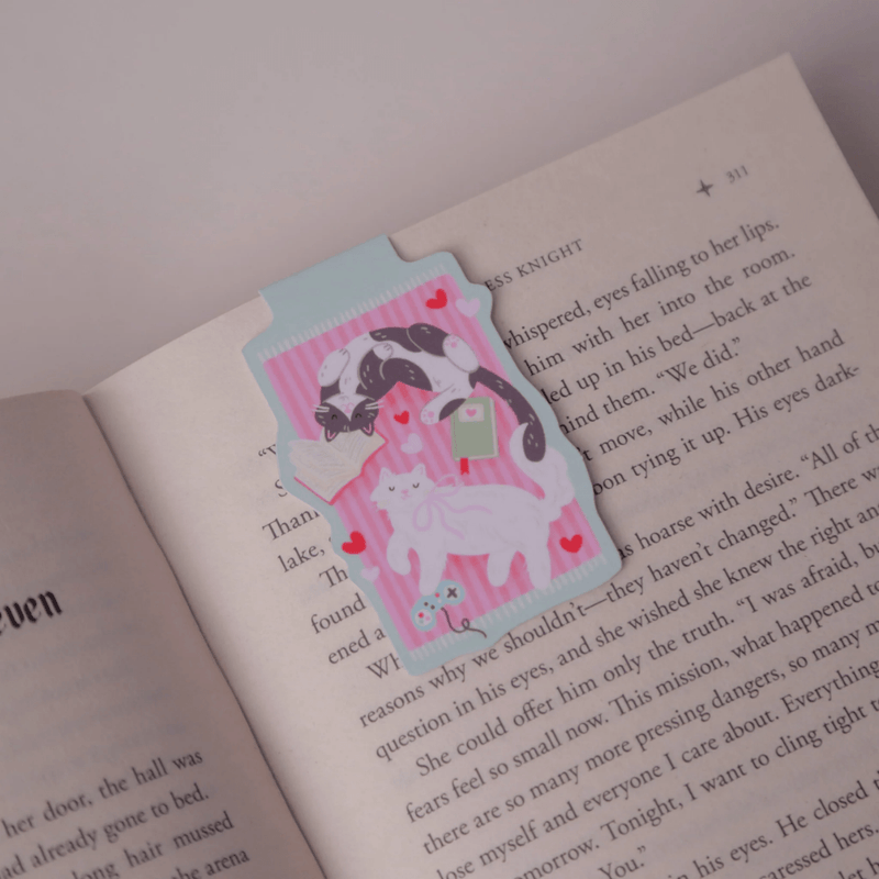 Cosy Cats magnetic bookmark clipped over the page of an open book