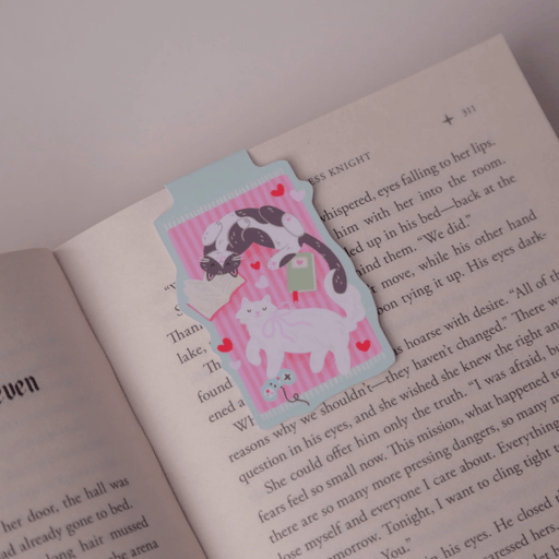 Cosy Cats magnetic bookmark clipped over the page of an open book