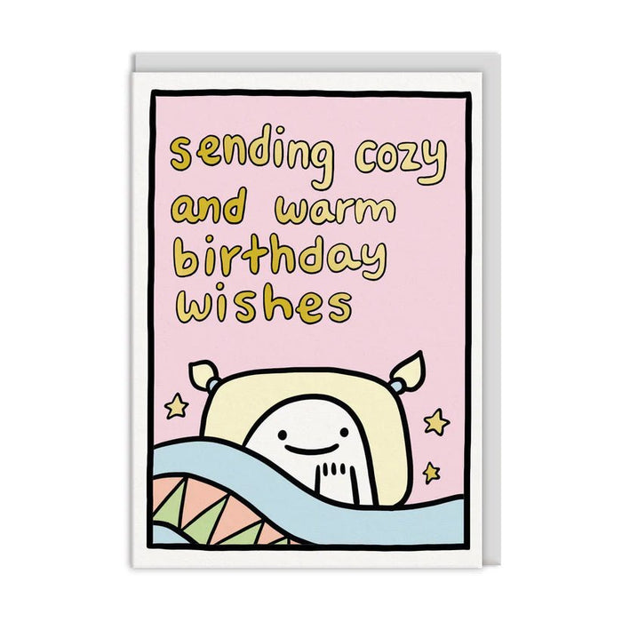 Pastel pink birthday card reading sending cozy and warm birthday wishes; cute character tucked in bed; A6 with white envelope