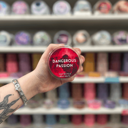Dangerous Passion wax melt pot held in hand with colourful wax melt display in the background