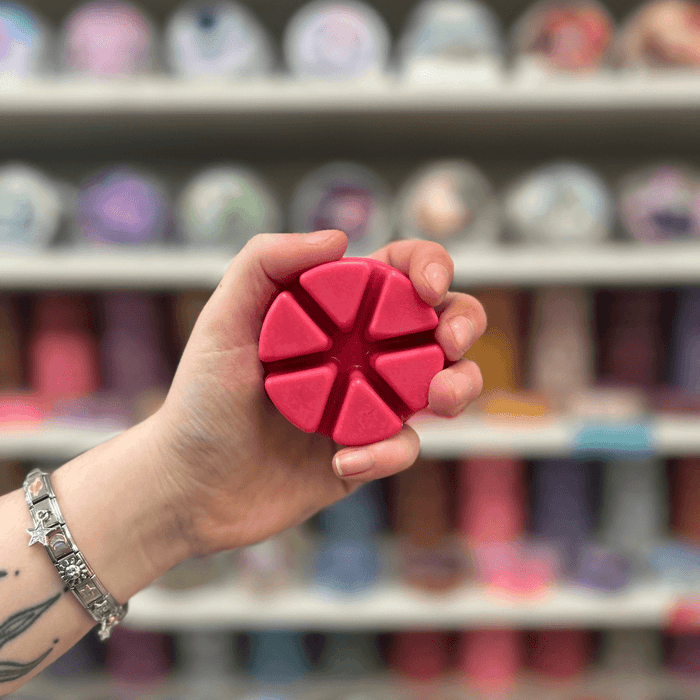 Dangerous Passion wax melt segments held in hand with colourful wax melt display in the background