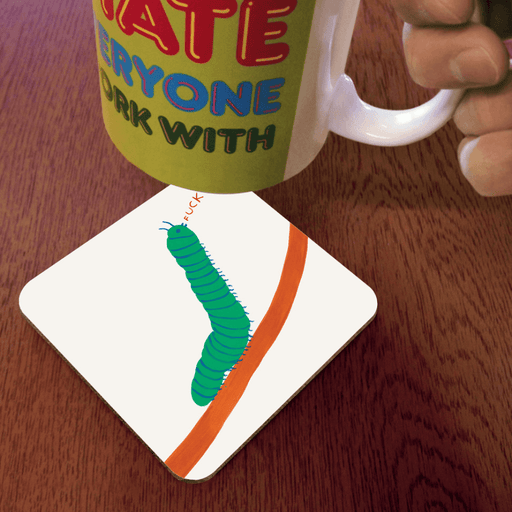 David Shrigley Caterpillar Fuck coaster shown in use under a mug on a wooden table