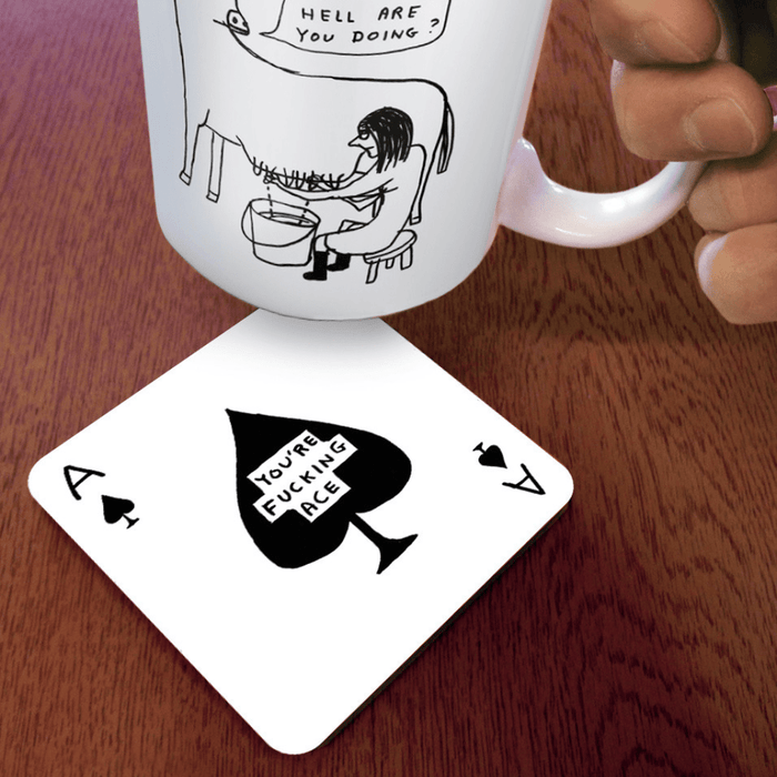 Effing Ace coaster on wooden table under illustrated mug, spade graphic and swear caption visible at an angle.

