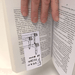 Bookmark gripping pages as a hand turns the book; Shrigley thumbs-up design visible upside-down.
