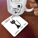 Lost Cat coaster on wooden table under illustrated mug; quirky black cat design visible at an angle.
