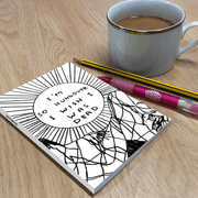 Lifestyle image: humorous hungover notebook on wooden desk beside mug of tea, pencil and pink pen.