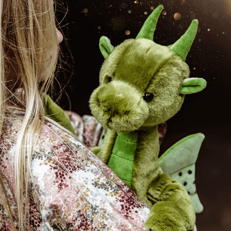 Deck green dragon teddy from Bearhouse by Charlie Bears 2025 being cuddled, showing soft plush face, horns and wings
